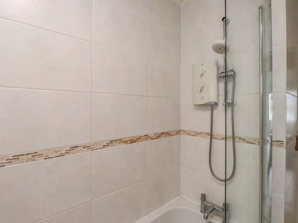 A bathroom with a shower and bathtub at Machroes Cottage Bwlchtocyn near Abersoch