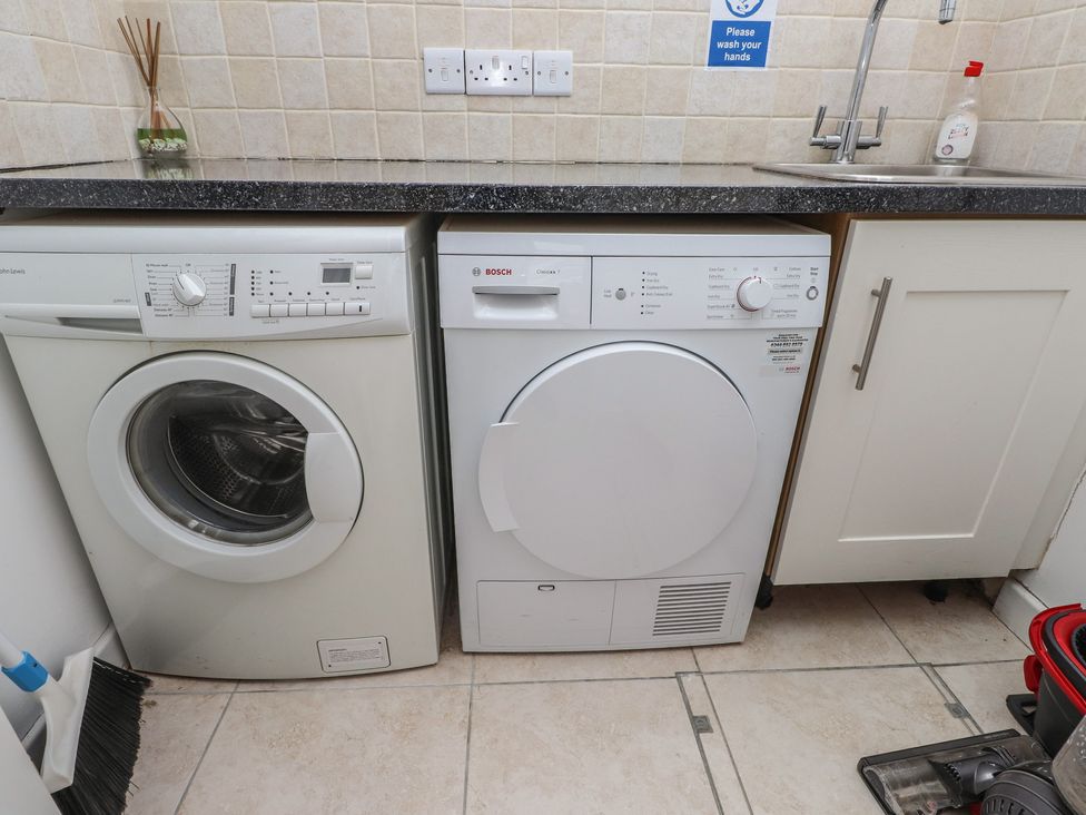 A laundry room with a washing machine and tumble dryer at Machroes Cottage in Bwlchtocyn near Abersoch