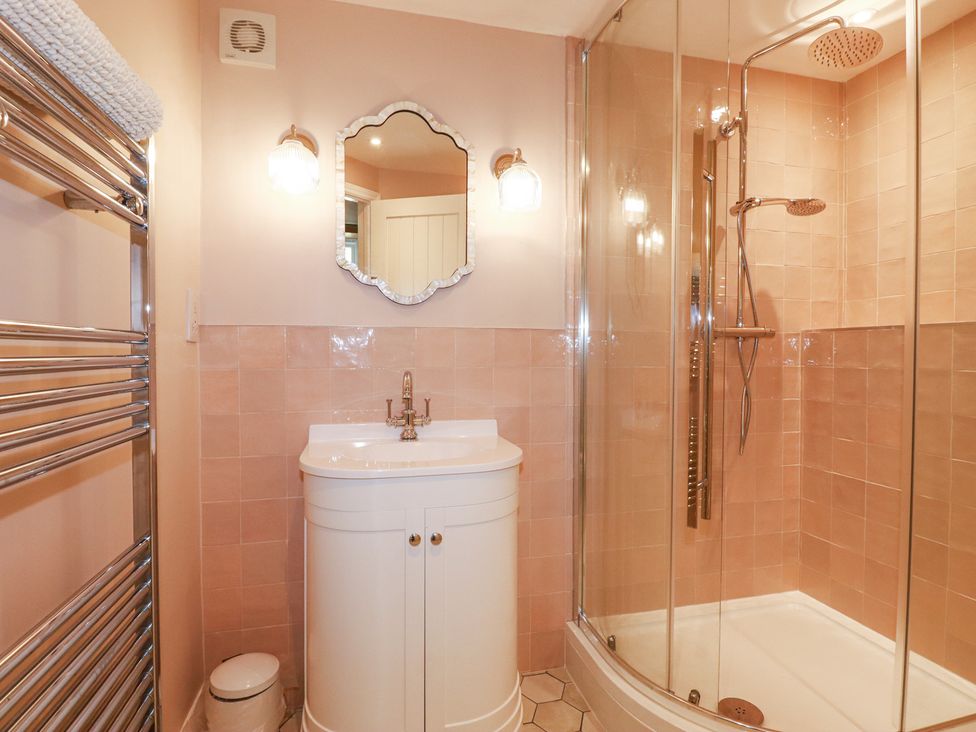 A bathroom with a vanity sink a glass shower enclosure a towel rack and a mirror at Roses Stable in Bodrean near Truro