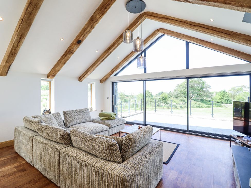 A living room with a sofa facing a large window at Perth Y Deri in Llanddwywe