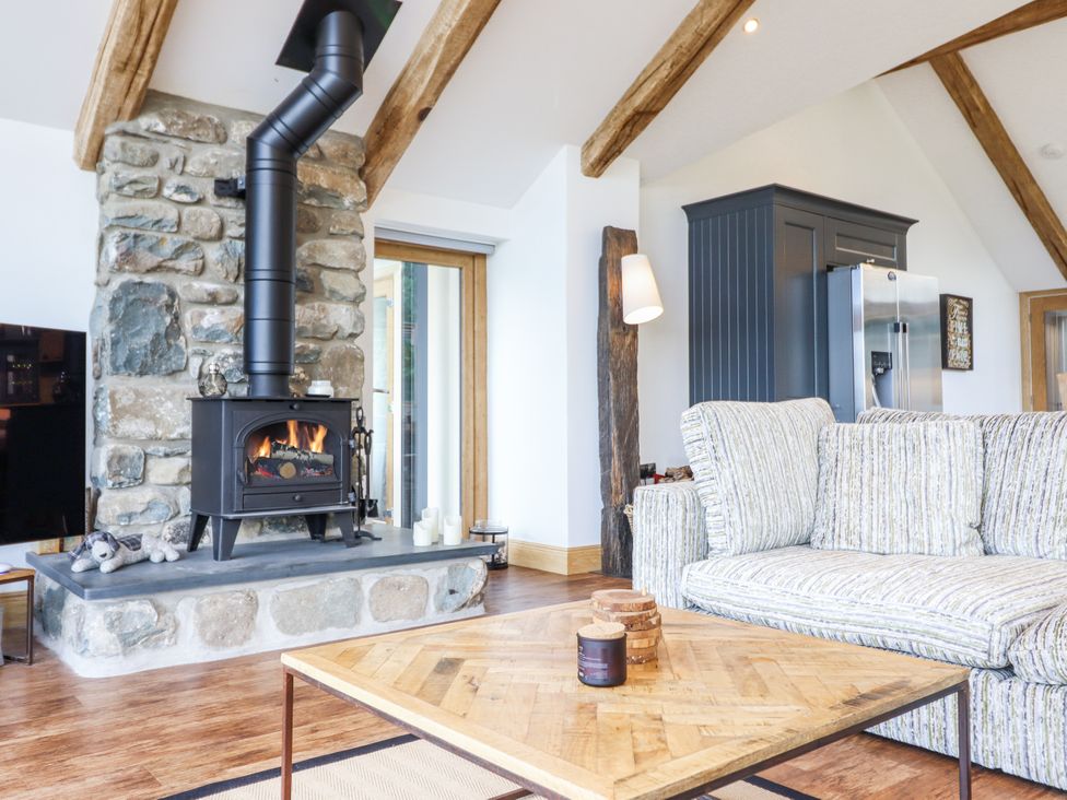A living room with a fireplace and sofa at Perth Y Deri in Llanddwywe