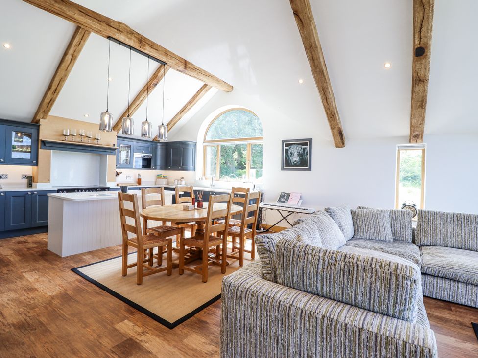 A kitchen and living area with a dining table and sofa at Perth Y Deri in Llanddwywe