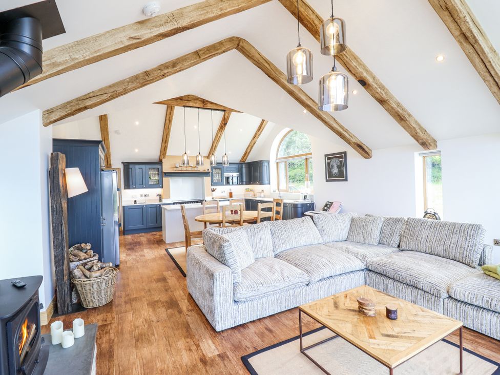 A living room with a sofa and kitchen area at Perth Y Deri in Llanddwywe