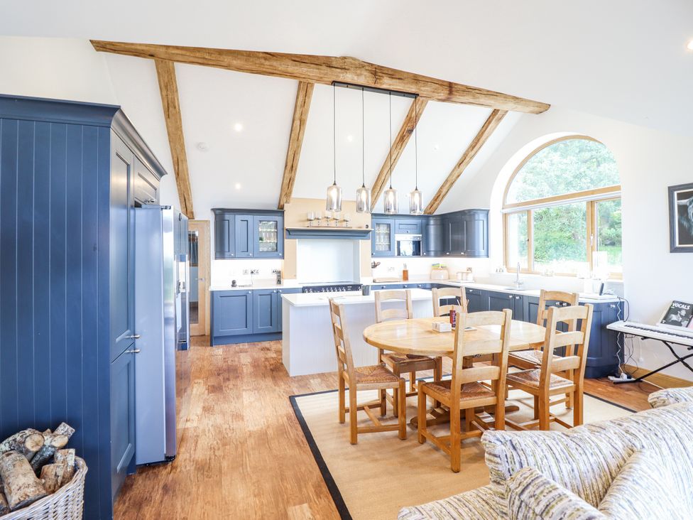 A kitchen with a dining table and chairs at Perth Y Deri in Llanddwywe