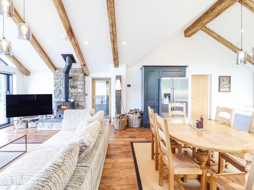 A living room with a sofa and dining area at Perth Y Deri in Llanddwywe