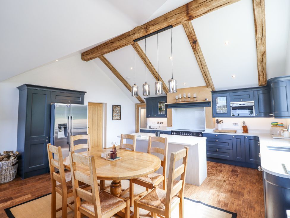 A kitchen with a dining table and chairs at Perth Y Deri in Llanddwywe