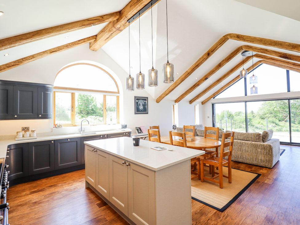 A kitchen with dining area and large windows at Perth Y Deri in Llanddwywe