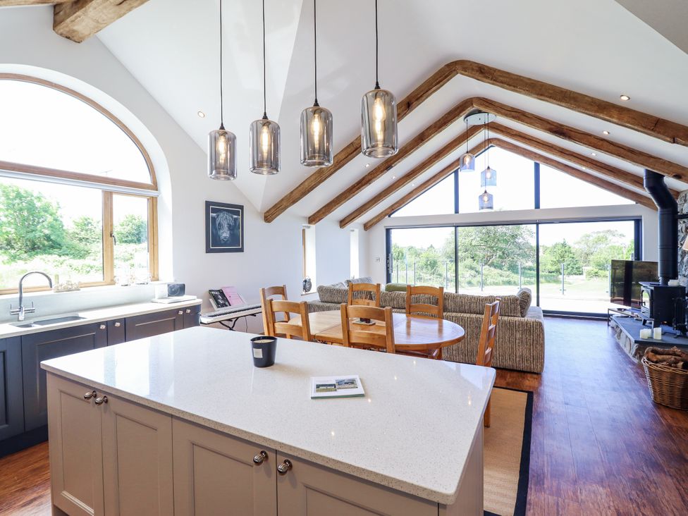 A kitchen with dining area and large windows at Perth Y Deri in Llanddwywe