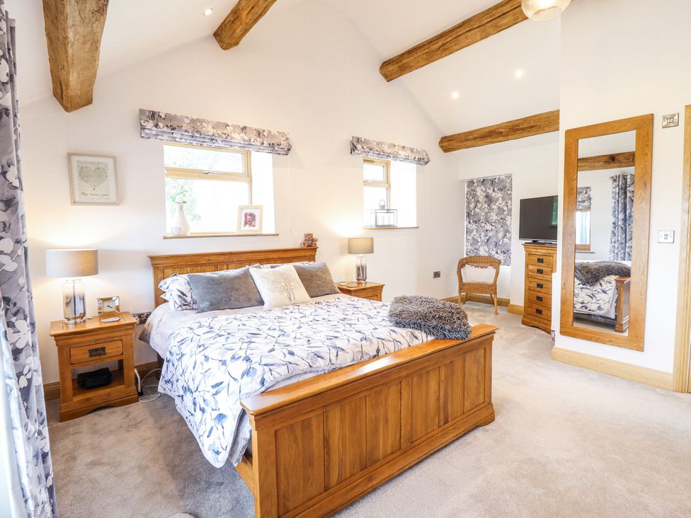 A bedroom with a wooden bed and nightstand at Perth Y Deri in Llanddwywe