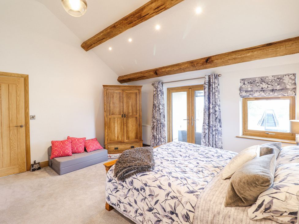 A bedroom with a bed and wardrobe at Perth Y Deri in Llanddwywe