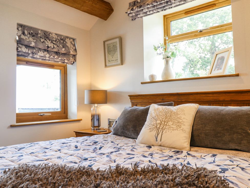 A bedroom with a bed and windows at Perth Y Deri Llanddwywe