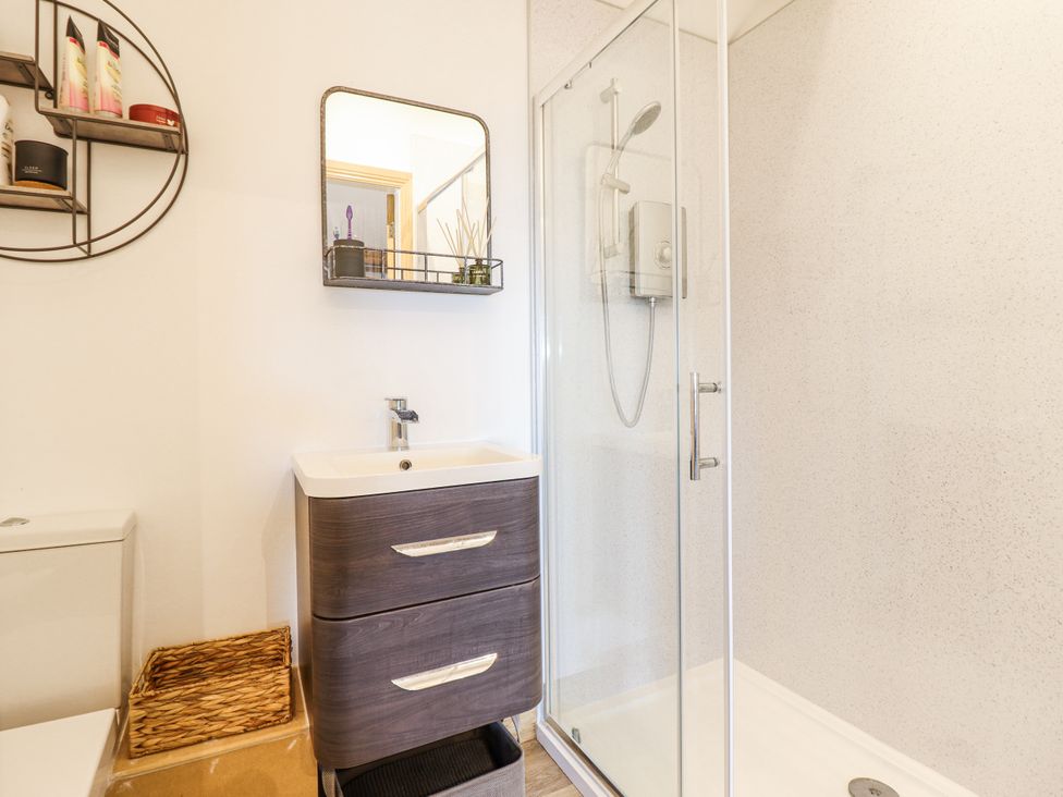 A bathroom featuring a shower and a sink with a mirror at Perth Y Deri in Llanddwywe