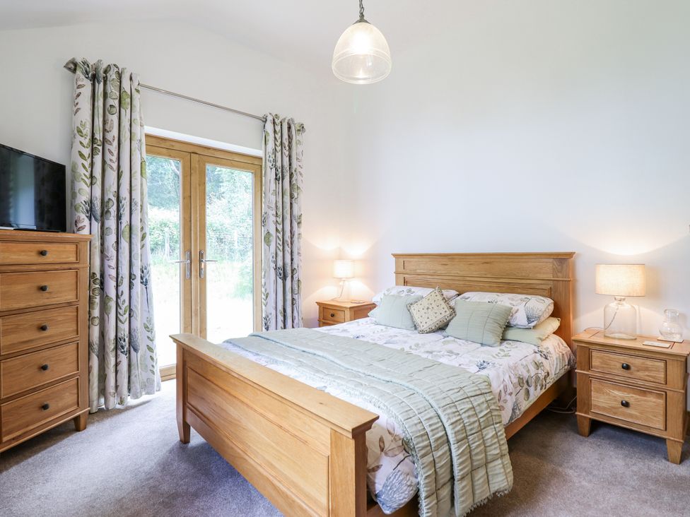 A bedroom with a bed and dresser at Perth Y Deri in Llanddwywe