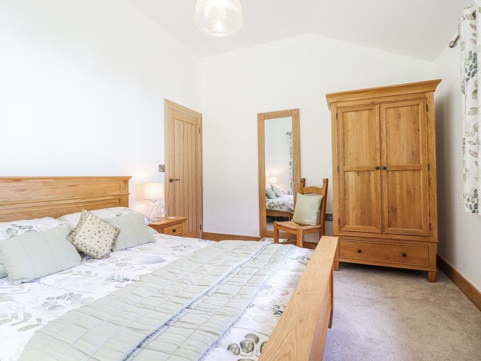 A bedroom with a bed and wardrobe at Perth Y Deri in Llanddwywe