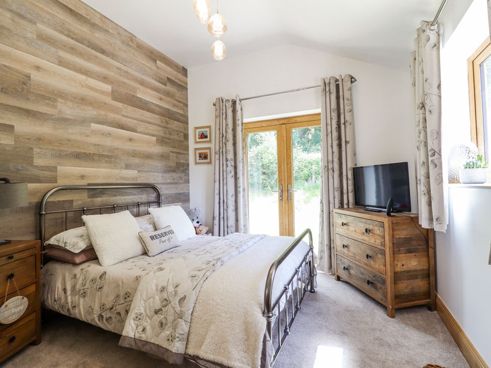 A bedroom with a bed and television at Perth Y Deri Llanddwywe