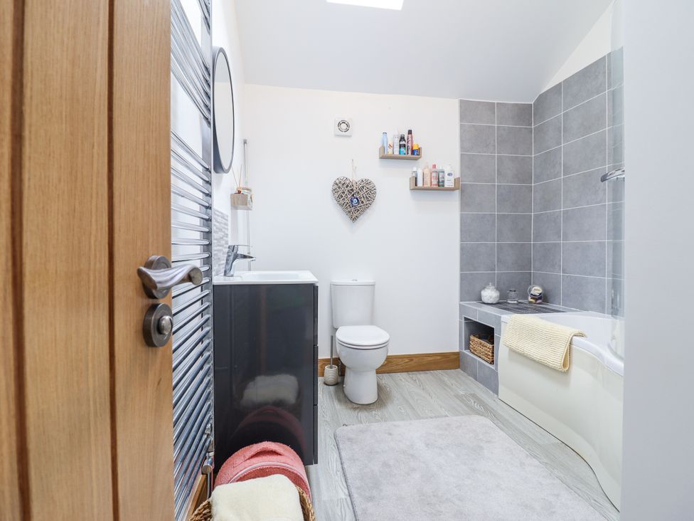 A bathroom with a sink and bathtub at Perth Y Deri in Llanddwywe