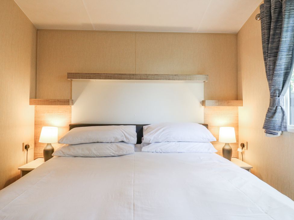 A bedroom with a bed and lamps at White Hart Caravan in Battle