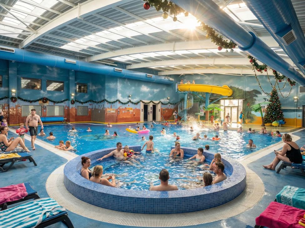 An indoor pool area with a water slide and people swimming at Starlight Skylight - Billing Aquadrome