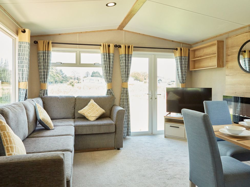 A living room with a sofa, television, and dining table at Meadowview - Billing Aquadrome
