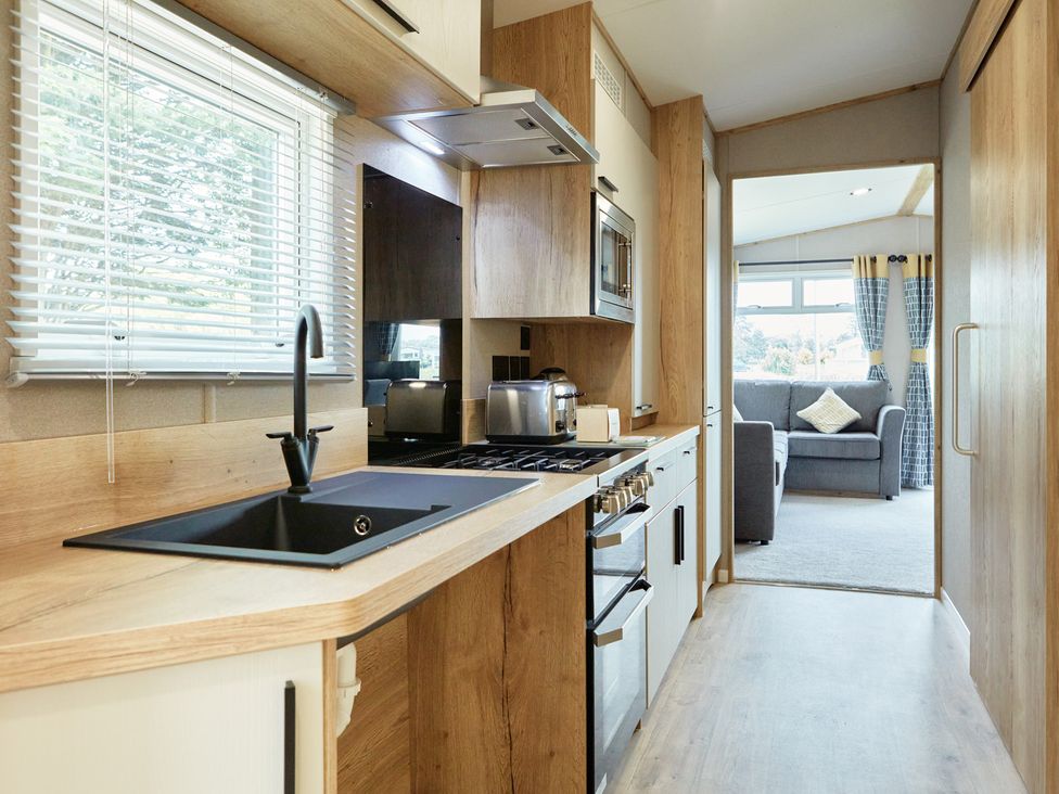 A kitchen with modern appliances and a view to a living area at Meadowview - Billing Aquadrome