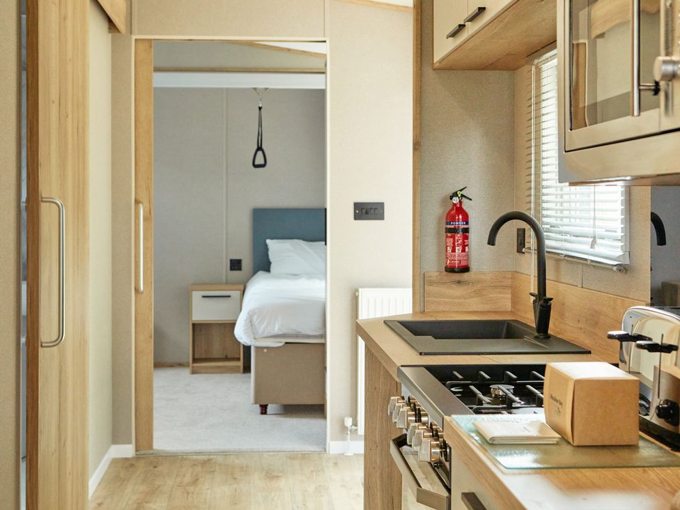 A kitchen with a stove and sink leading to a bedroom at Meadowview - Billing Aquadrome