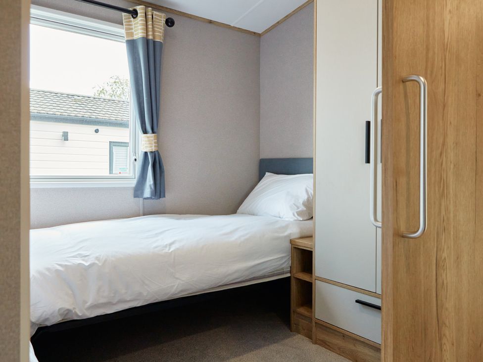 A bedroom with a bed and a wardrobe at Meadowview - Billing Aquadrome