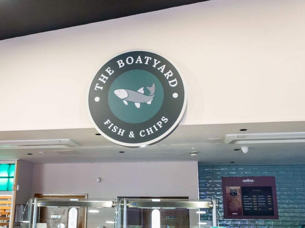 An indoor food area with a sign reading The Boatyard Fish and Chips above the counter