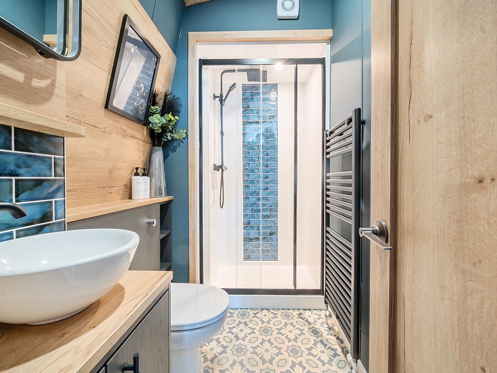 A bathroom with a shower enclosure a toilet a sink with wooden countertop and patterned tile floor at Moonlit Skylight - Billing Aquadrome Billing Aquadrome Holiday Park