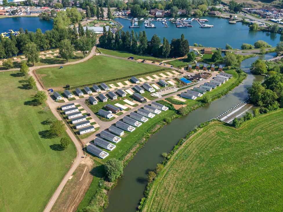 A holiday park with rows of static caravans near a river and a lake with boats at Billing Aquadrome Holiday Park