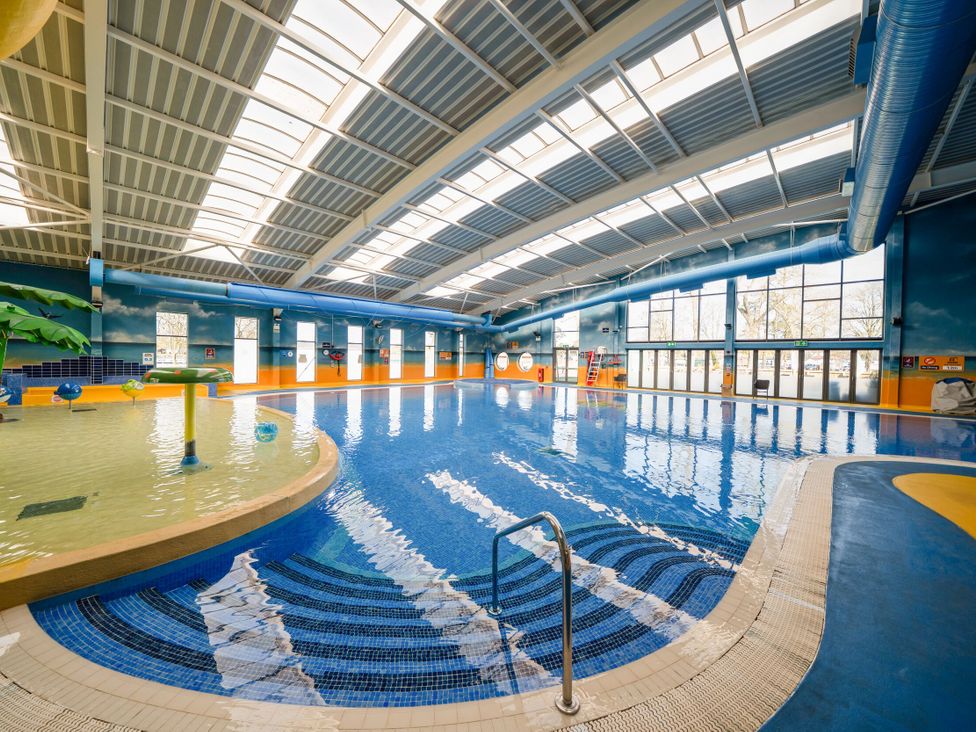An indoor swimming pool with a shallow children's area and large windows at Brookside Bliss - Billing Aquadrome Billing Aquadrome Holiday Park