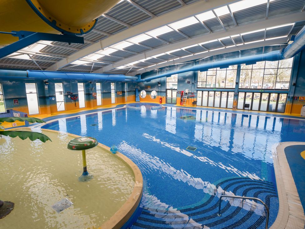 An indoor swimming pool with a shallow kid's area and large windows at Brookside Bliss - Billing Aquadrome in Billing Aquadrome Holiday Park