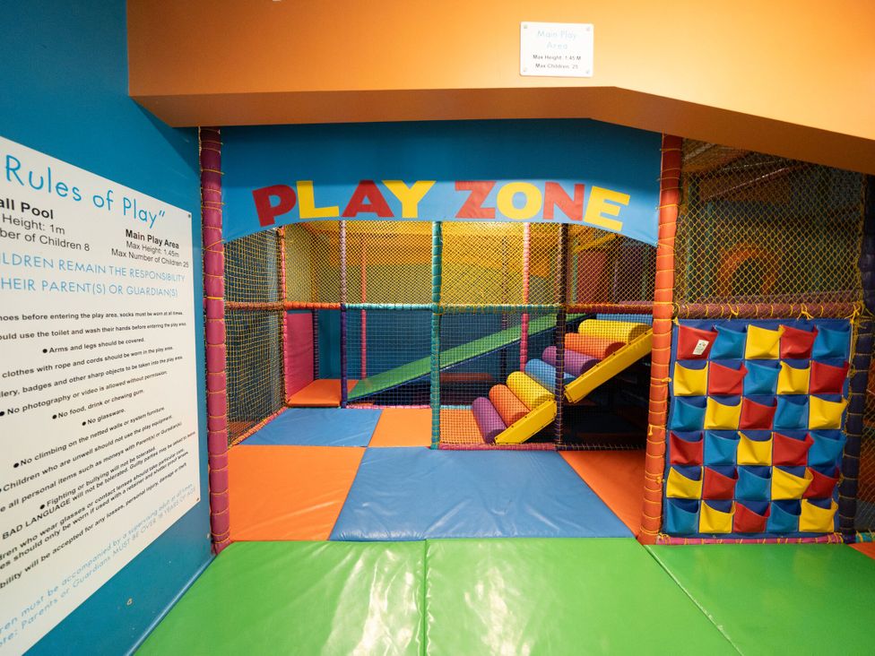 An indoor play area with padded floor mats climbing nets and a sign with play rules at Brookside Bliss - Billing Aquadrome Holiday Park