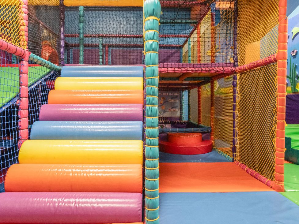 An indoor soft play area with padded climbing steps and netted walls at Brookside Bliss Billing Aquadrome Holiday Park