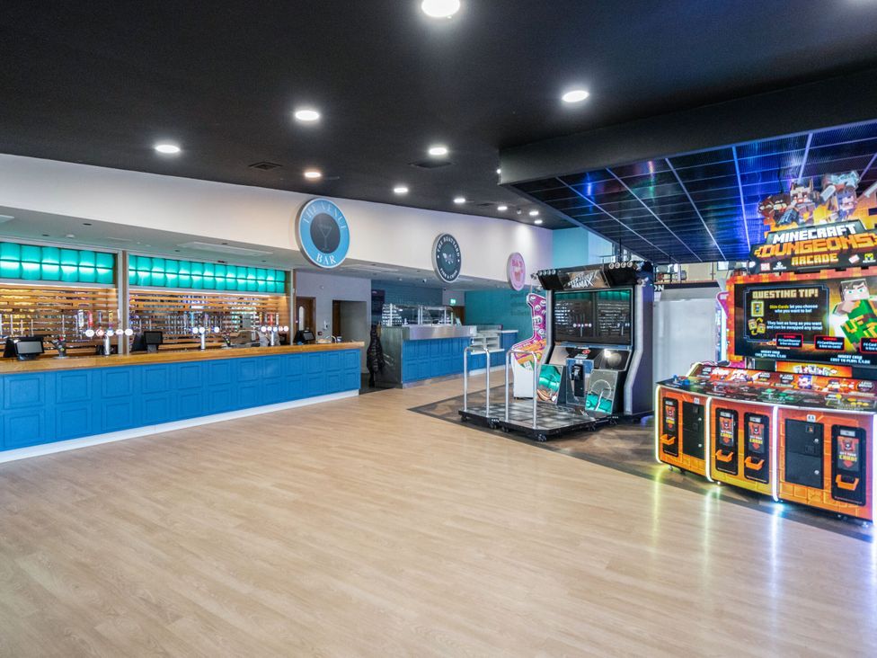 An arcade room with a blue bar counter and game machines including Minecraft Dungeons at Brookside Bliss Billing Aquadrome