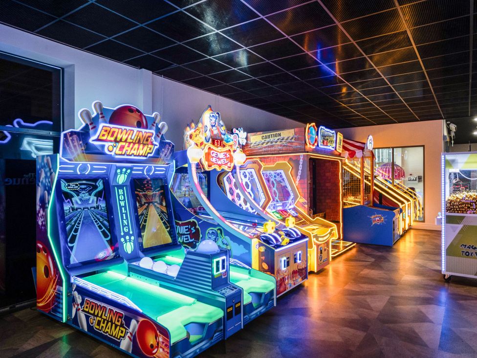 An indoor arcade with a bowling game bowling champ and several other illuminated arcade machines
