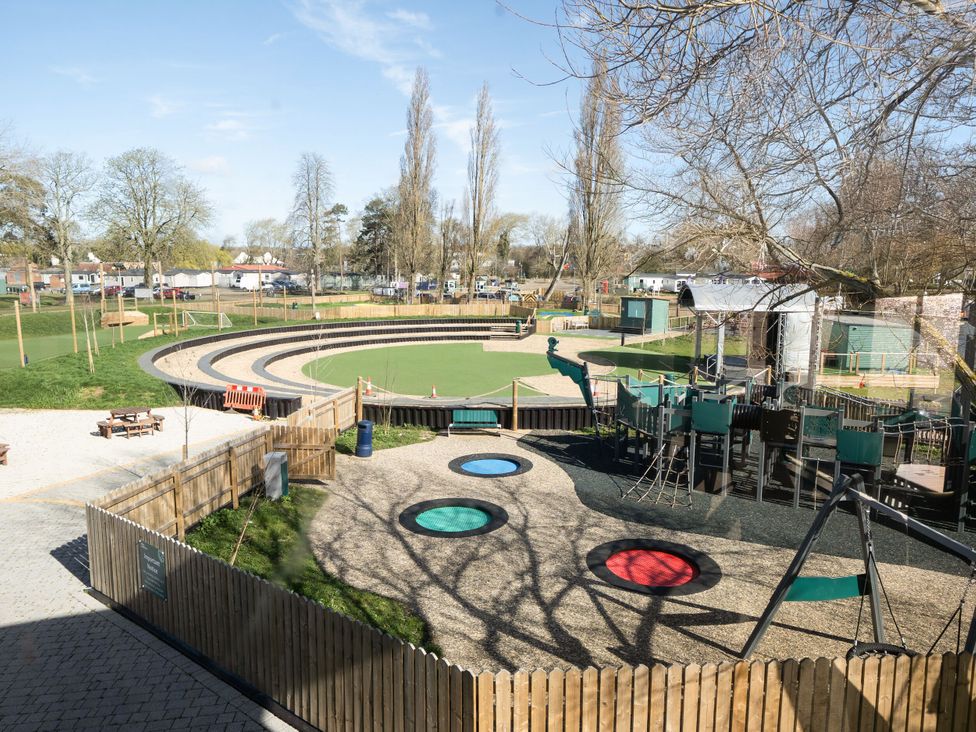 An outdoor playground with trampolines swings climbing structures and an amphitheater at Brookside Bliss in Billing Aquadrome Holiday Park