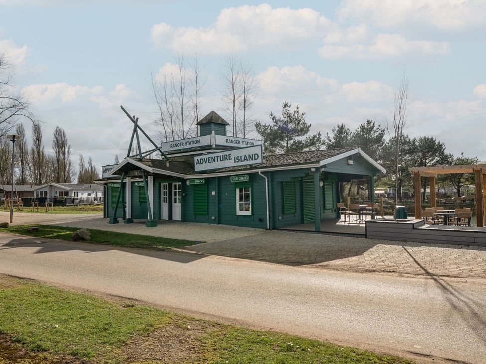 An adventure island ranger station building with outdoor seating and signs for snacks cold drinks ice cream and teas and coffees at Billing Aquadrome Holiday Park