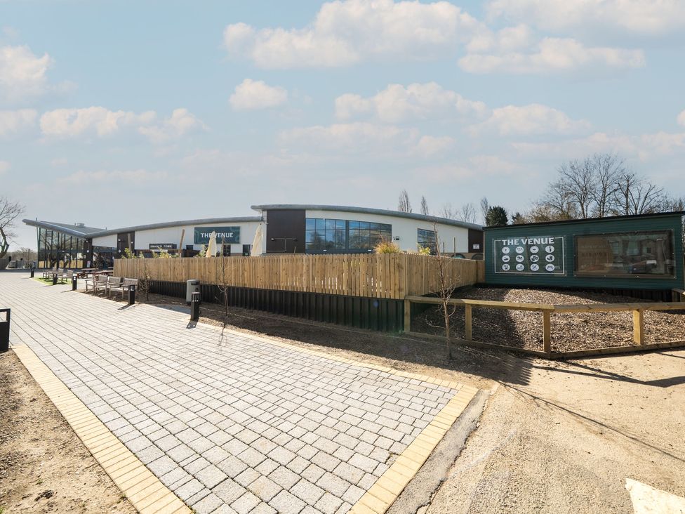 A paved walkway leading to a building with a sign reading The Venue at Billing Aquadrome Holiday Park