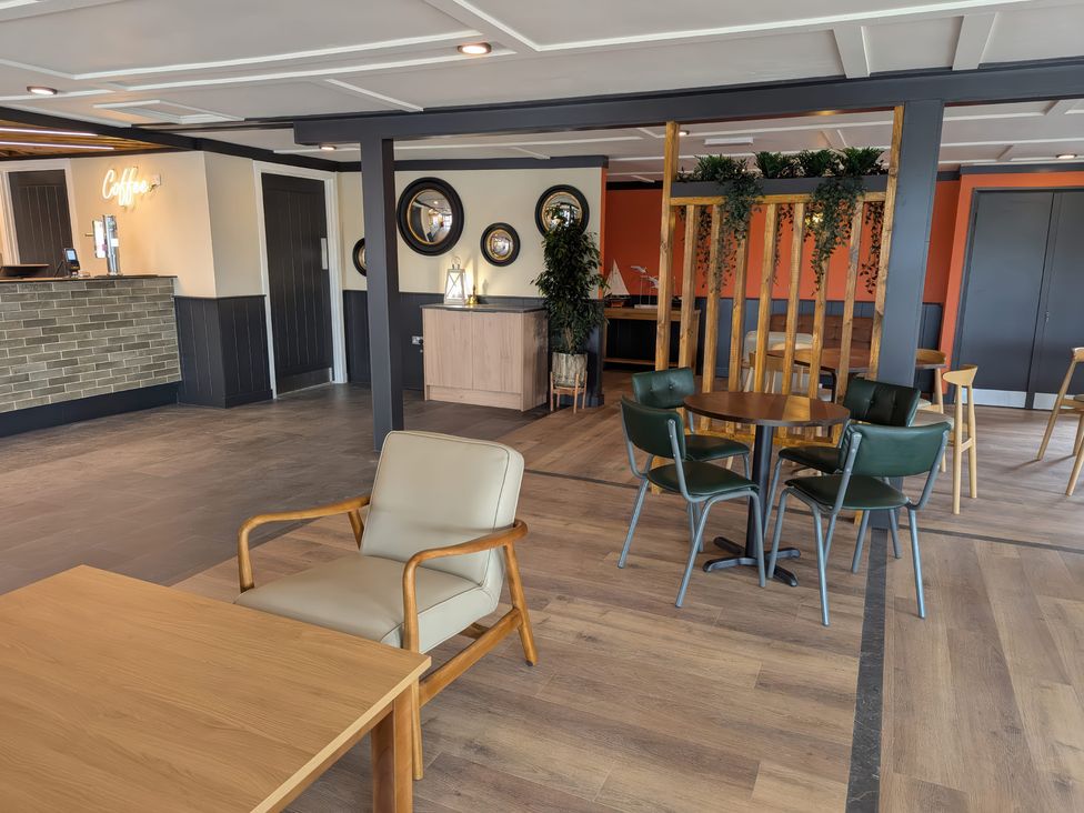 A seating area with chairs and tables in a room with a coffee counter and decorative mirrors at Brookside Bliss Billing Aquadrome