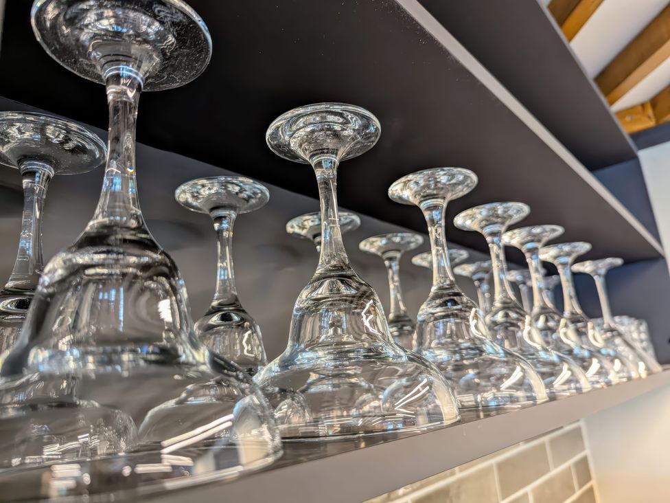 A row of upside down wine glasses on a shelf in a bar or kitchen