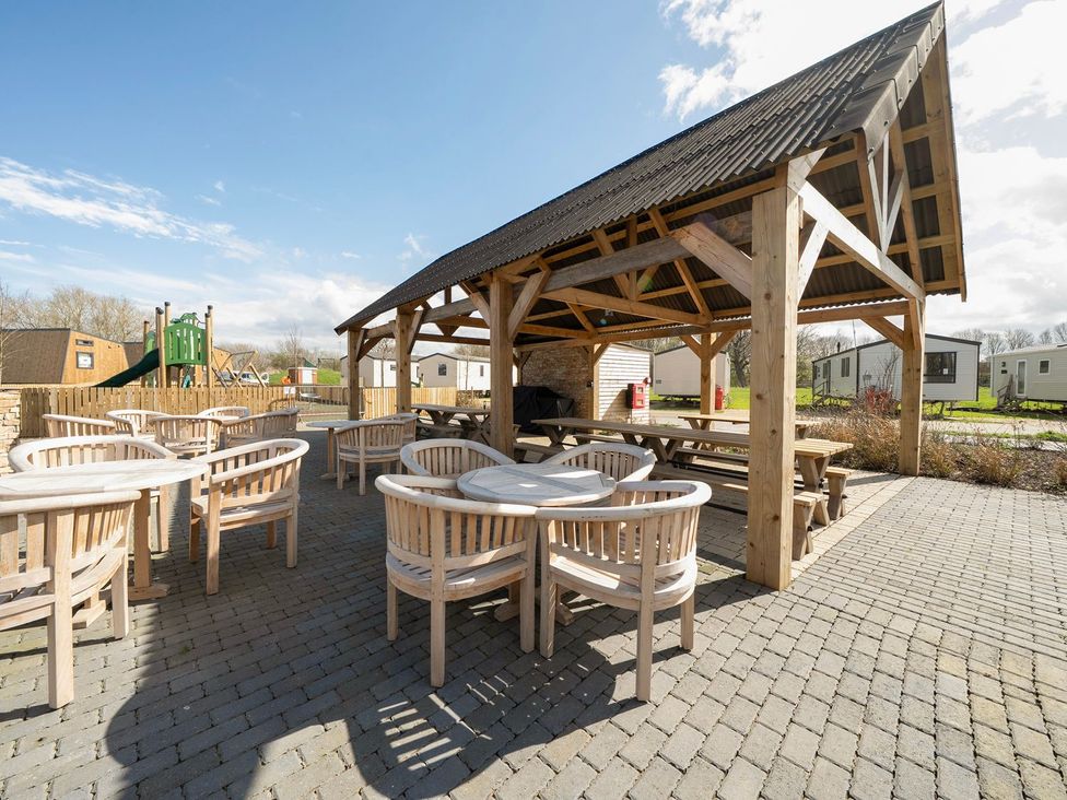 An outdoor seating area with wooden furniture and a covered structure at Brookside Bliss - Billing Aquadrome