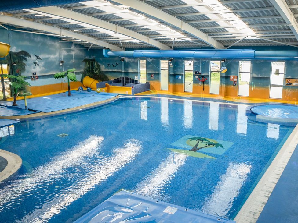 An indoor pool area with a swimming pool and water slide at Brookside Bliss - Billing Aquadrome