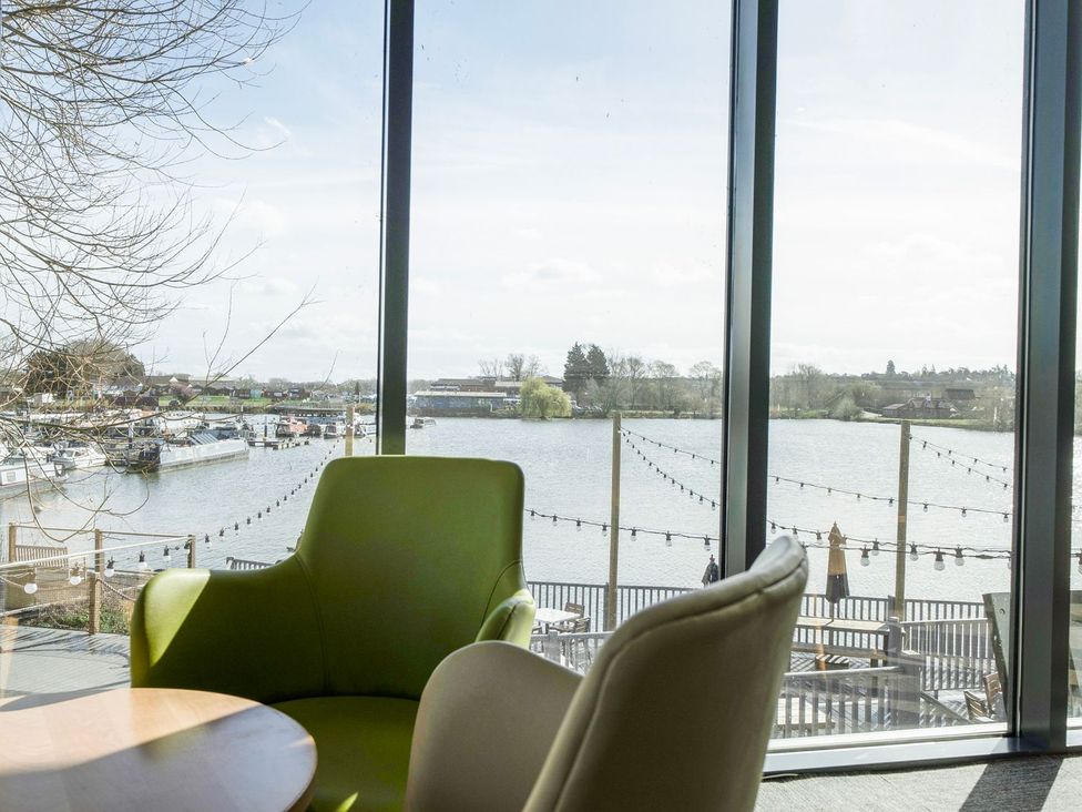 A room with a green chair and table overlooking a river at Brookside Bliss - Billing Aquadrome