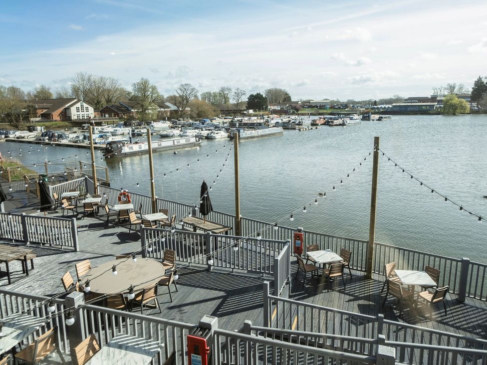 An outdoor area with tables and chairs overlooking a water body at Brookside Bliss - Billing Aquadrome