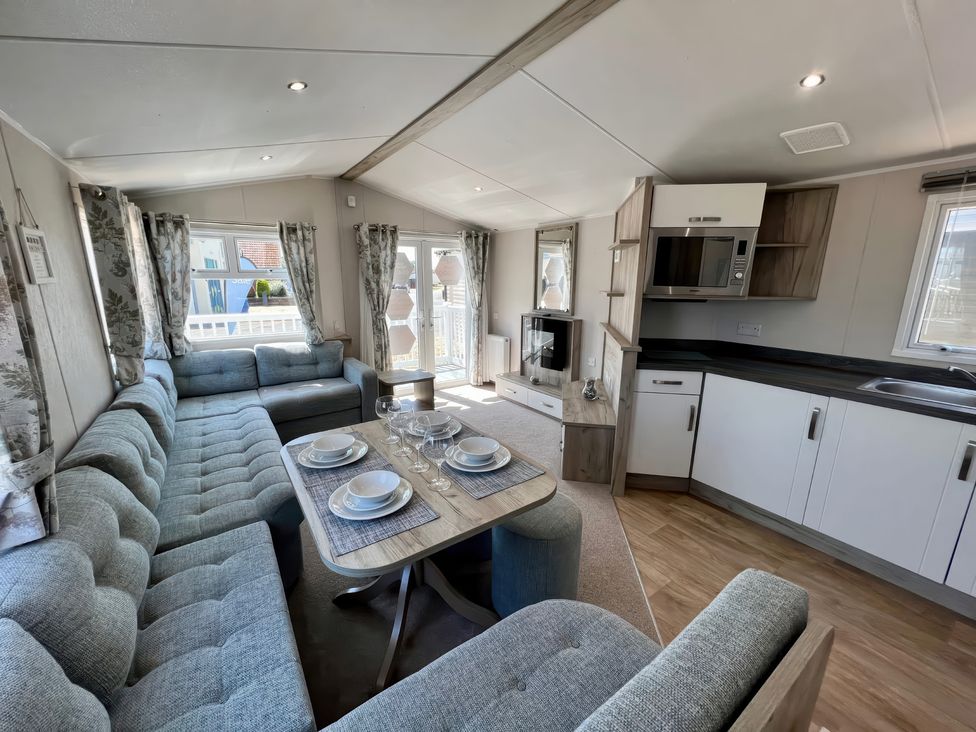 A living room with a sofa and dining table at Seagull's Sanctuary - Hayling Island