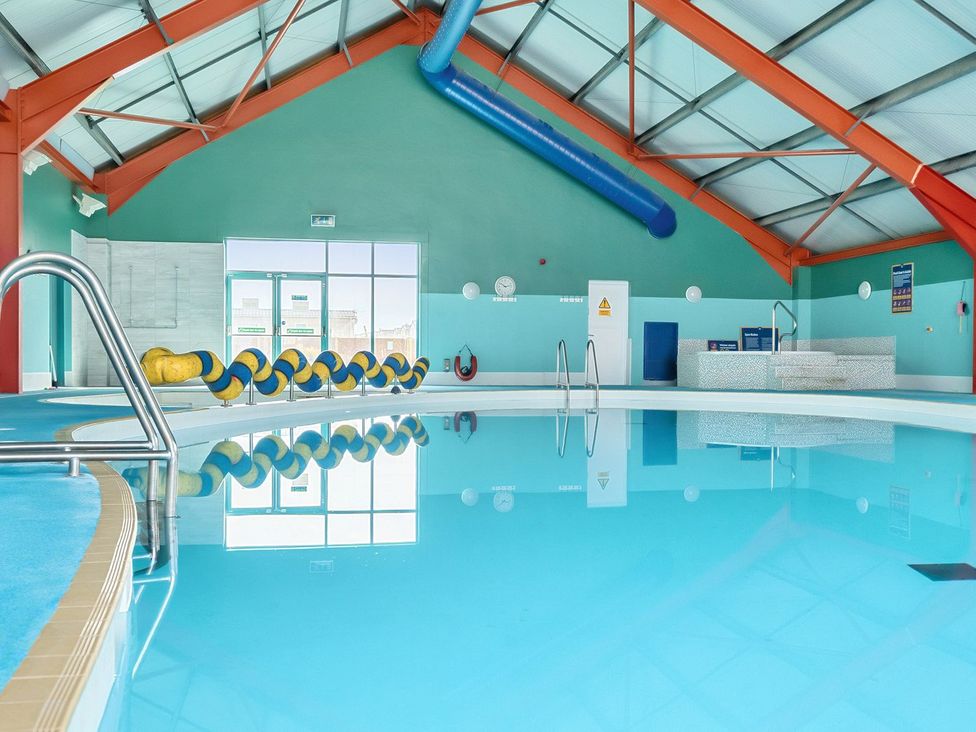 An indoor swimming pool with blue and yellow pool noodles and a hot tub at Mariner's Meadow - Hayling Island Holiday Park
