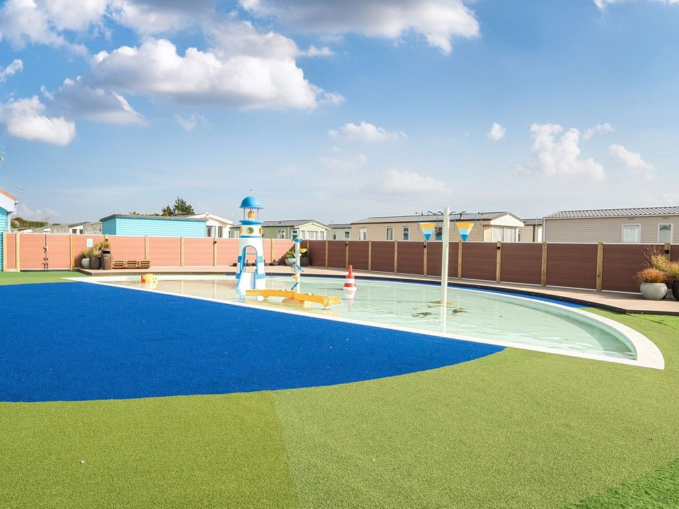 An outdoor shallow pool with water features and artificial turf at Mariner's Meadow - Hayling Island in Hayling Island Holiday Park