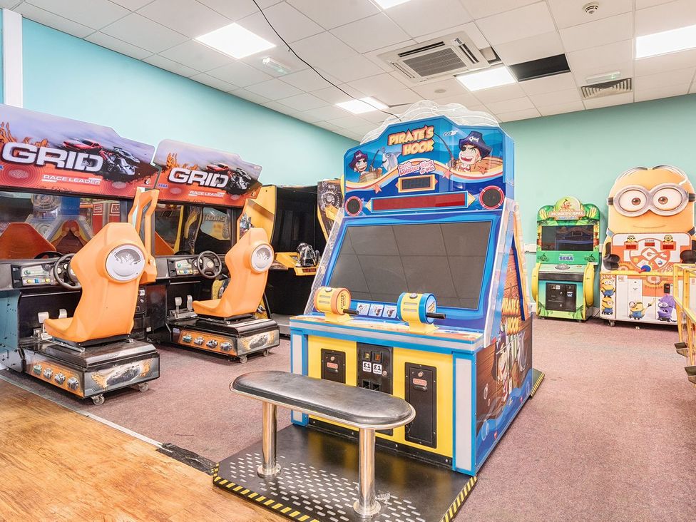 An arcade room with racing game seats and a pirate themed game at Seaside Serenity Hayling Island Holiday Park
