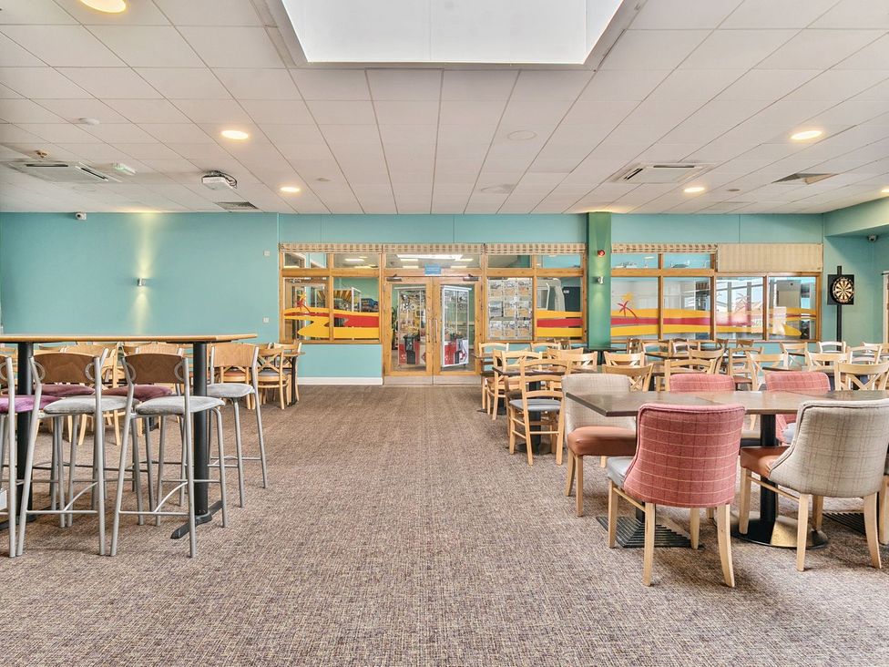 An empty dining area with tables and chairs and blue walls at Seaside Serenity - Hayling Island in Hayling Island Holiday Park
