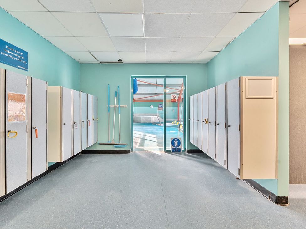 A changing room with lockers and cleaning tools leading to a swimming pool at Seaside Serenity - Hayling Island Hayling Island Holiday Park